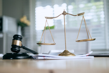 A wooden gavel rests on a stack of documents beside a laptop, symbolizing power and justice.