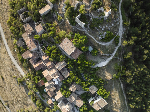 Aerial view of ancient stone buildings clinging to a hilltop, kissed by sunlight, Rocca Calascio, Abruzzo, Italy.