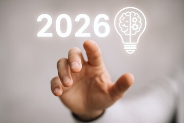 Fototapeta premium Innovative Vision: Hand Reaching Towards the Year 2026 with a Symbolic Lightbulb Brain