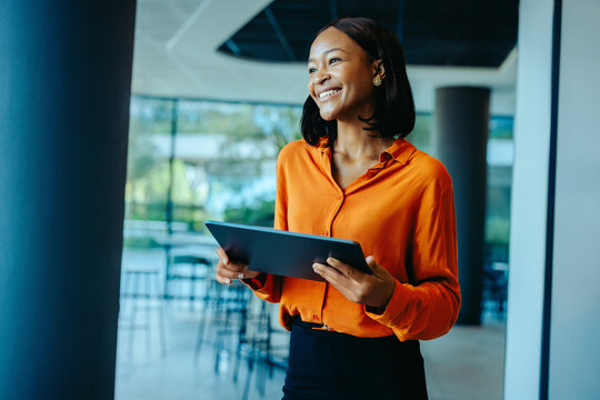 Confident African business executive using tablet in modern office setting