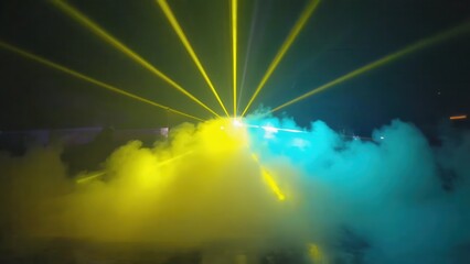 Yellow and cyan laser beams illuminating smoke machine fog in nightclub