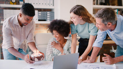 Obraz premium Staff Celebrating Birthday Of Female Colleague In Architects Office With Cake