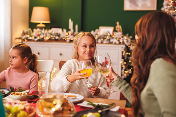 Mother making a toast with daughters while having Christmas dinner at home