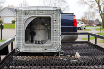 A broken washing machine sitting outside on a trailer