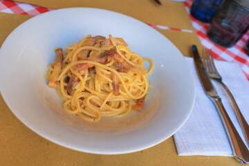 A plate of traditional pasta carbonara served in a cozy Italian restaurant in Verona. Diners savor the rich flavors of the dish in a warm, inviting atmosphere.