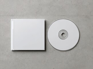 Blank white CD and its square jewel case rest on a speckled gray surface;  a minimalist, top-down product shot