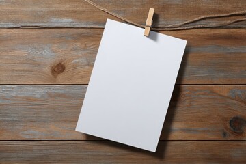 Blank white paper hangs from twine on a rustic wooden background; simple, minimalist aesthetic