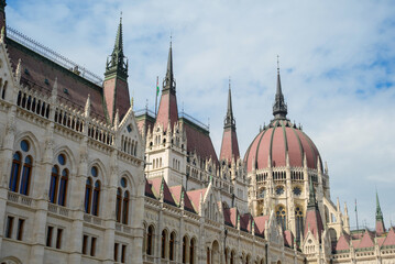 Fototapeta premium Stunning view of the Hungarian Parliament building in Budapest. The intricate design features tall spires and a distinctive dome against a clear sky, showcasing Gothic Revival architecture.