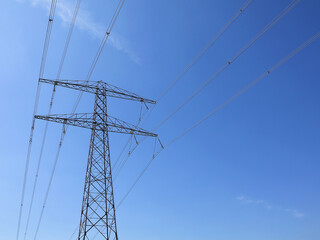 Fototapeta premium High voltage pylon with power lines against a blue sky. Electricity concept.