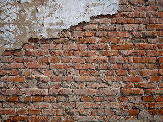 The texture of a very old vintage brick wall with residual elements of plaster decoration.