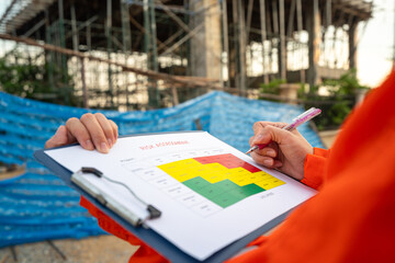 Action of a project manager is writing on risk assessment matrix form to rating the risk of house...