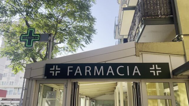 Pharmacy Sign: A modern pharmacy with a prominent illuminated sign, indicating readily accessible healthcare and medication within a bustling urban landscape. Rimini, Italy