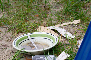 Fototapeta premium Old dirty plate with spoon and trash on wet ground