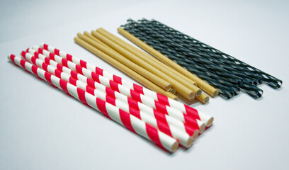 Variety of drinking straws with eco and plastic options on white paper, plastic and cardboard