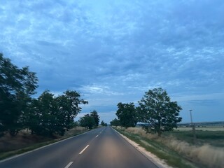 Landscape of a road in dim light at sunset, perspective, cloudy sky. 