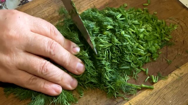 Chopping of fresh dill bundle on cutting board, slow motion