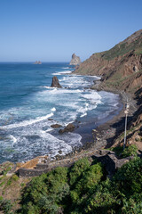 Stunning coastal view showcasing rocky cliffs and crashing waves at a serene beach during a clear day