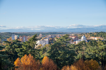 Colorful autumn landscape showcasing city skyline and distant mountains in a clear blue sky during daylight