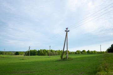 Expansive green field with utility poles under a clear sky in a rural landscape, showcasing tranquility and nature's beauty in late afternoon light