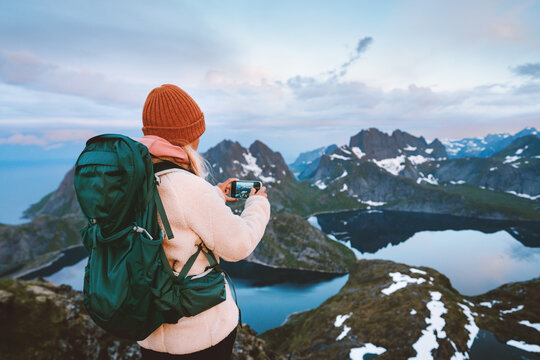 Woman travel blogger using smartphone camera in Norway traveler hiking solo with backpack in Lofoten islands mountains, adventure vacations eco tourism active healthy lifestyle hobby outdoor