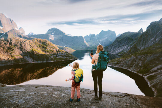Family mom and child hiking in Norway travel in Lofoten islands woman taking photo using smartphone mountains and lake view, active vacations navigation application technology camping trip outdoor