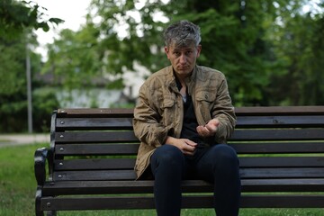 Obraz premium Homeless man begging for money on bench in park