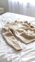 Beige cable knit sweater on bed (1)
