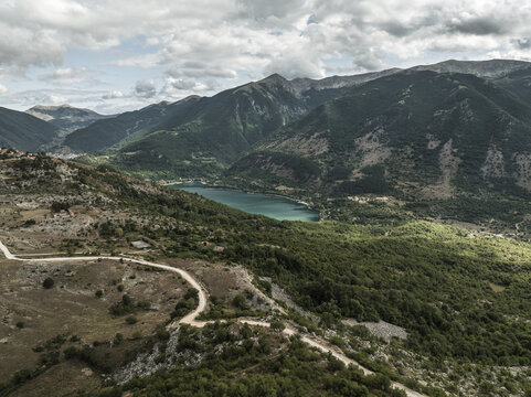 Aerial view of Lake Scanno nestled amongst the verdant mountains, a jewel of turquoise reflecting the sky, Contrada Frattura, Scanno, Abruzzo, Italy.