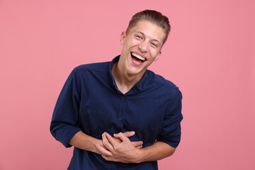 Handsome man laughing on pink background. Positive emotion
