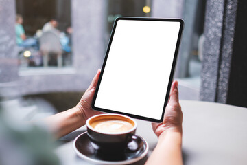 Mockup image of a woman holding digital tablet with blank white desktop screen in cafe
