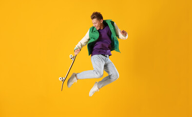 Fototapeta premium Man with skateboard jumping on orange background