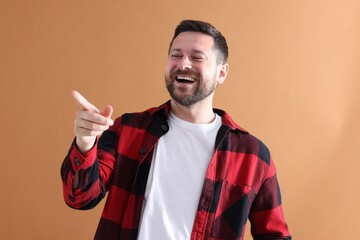 Handsome man laughing on dark beige background