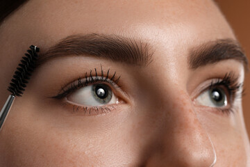 Fototapeta premium Young woman brushing her eyebrow with spoolie, closeup