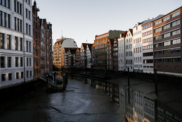Reflections of historic architecture along the canal in Hamburg during sunset illuminating the buildings' detailed facades