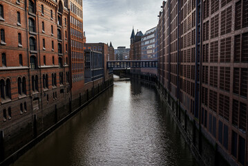 Historic canals reflect the architecture of Hamburg's warehouse district during a cloudy midday
