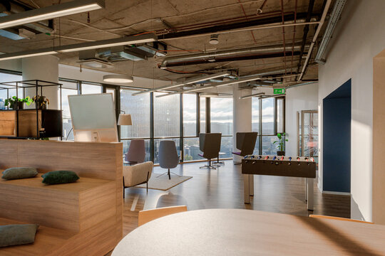 Modern office interior with large windows and relaxed seating area overlooking the city during daylight
