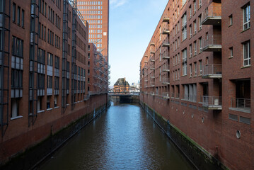 View of historic brick buildings lining a canal in Hamburg’s Speicherstadt district under a clear blue sky