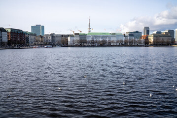 Obraz premium Cityscape by the waterfront showcases modern buildings and serene water surrounded by urban activity in Hamburg, Germany on a clear day