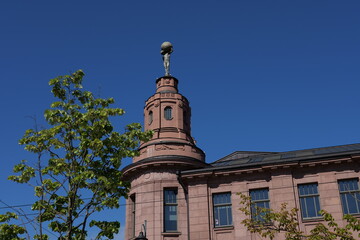Historic building with a statue on the dome against a clear blue sky in a vibrant urban setting during midday