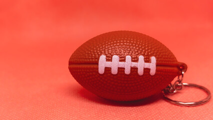 Dynamic Spirit: Football Keychain Popping Against a Vibrant Red Background