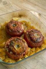 stuffed tomatoes with rice and herbs baked in glass dish served with potatoes