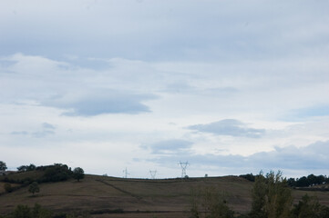 A landscape with power lines and a cloudy sky.