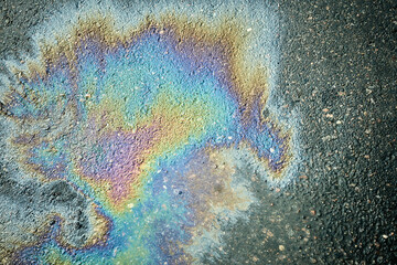 Gasoline or oil spill creating rainbow sheen on asphalt road surface