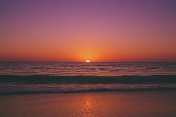Obraz premium Serene Sunset Over the Ocean: A tranquil view of the sun setting over the vast ocean.
