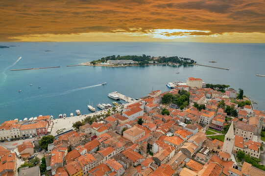 Historic Porec peninsula with dramatic orange sunset sky in Croatia.