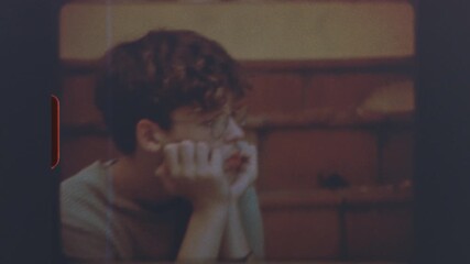 Teenage boy wearing glasses sitting on stairs in thoughtful pose on retro super 8mm vintage film - Powered by Adobe
