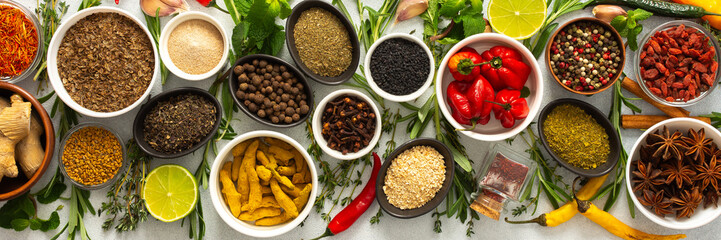 Assorted cooking spices and herbs arranged on a gray surface, featuring natural tones that add depth and aroma to any meal, banner