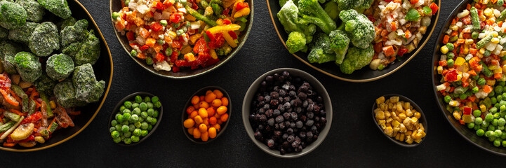 A selection of frozen fruits and vegetables neatly arranged in plates, with a dark background, highlighting the practice of preserving summer produce for winter, banner