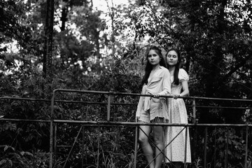 Portrait of young beautiful twin sisters outdoors. Black and white photo.