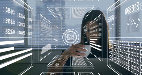 Analyzing businesswoman holding coffee mug at office desk, interacting with floating data panels